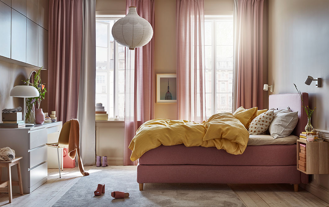 卧室配浅棕粉色的沙发床，黄色被套和枕套，白色灯具和白色梳妆台。
