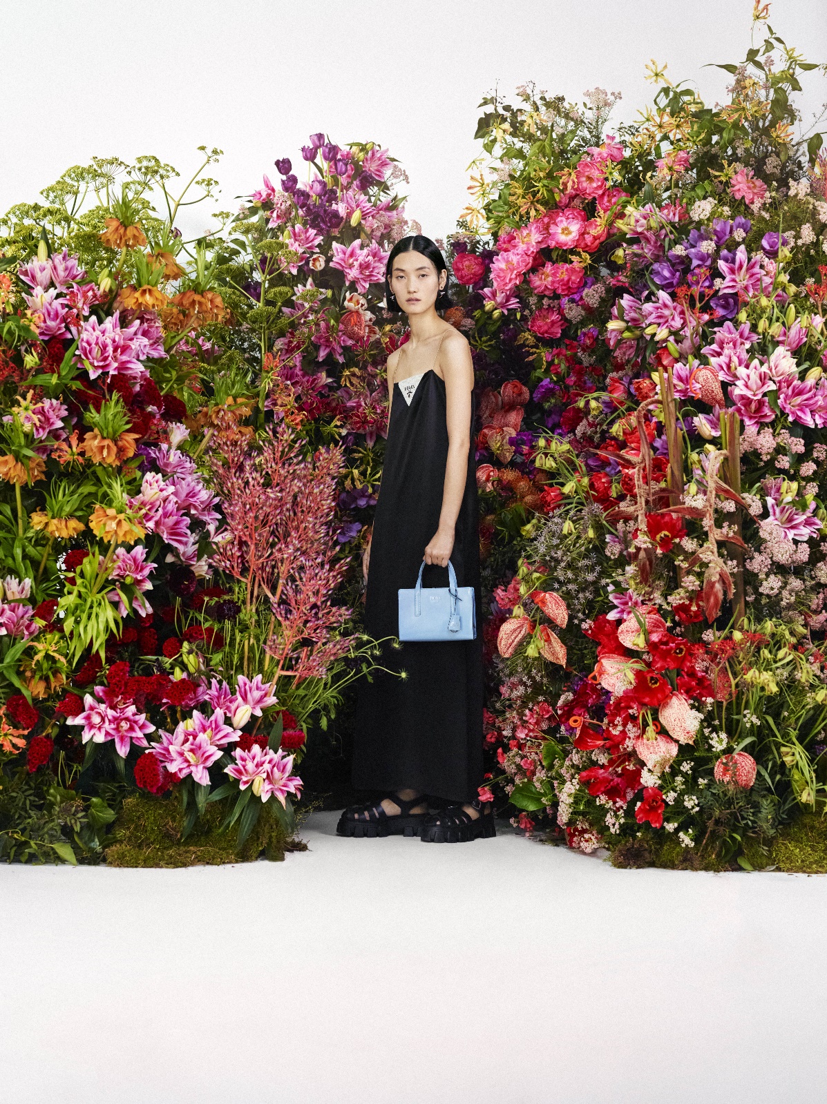A person standing in front of a bush of flowers

Description automatically generated with medium confidence